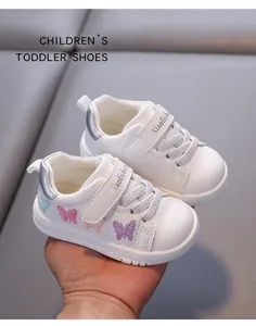 Detailed view of white toddler walking shoes featuring colorful butterfly embroidery and velcro.