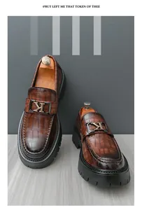 Macro view of brown alligator-patterned loafers with a metallic K-buckle accent.