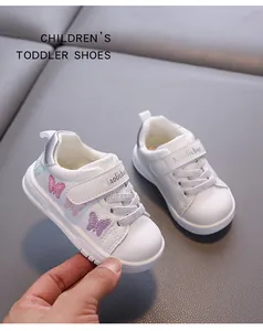 Macro view of white toddler shoes with colorful butterfly embroidery and silver glitter laces