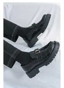 Macro view of black crocodile-pattern loafers with thick platform soles and H-buckle