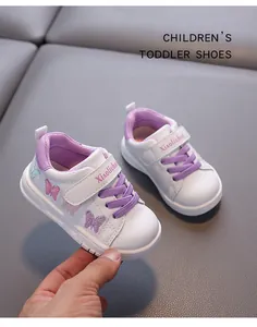 Detail of toddler white sneakers featuring purple laces and pink butterfly embroidery.