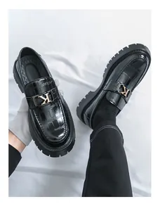 Close-up of black chunky loafers with crocodile texture and metal K-logo buckle detail