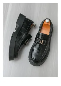 Close-up detail of mens black crocodile pattern leather loafers with metallic K buckle