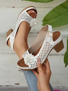 Detailansicht der weißen Sandalen mit Blockabsatz, Lochmuster und dekorativer Blumenverzierung