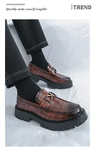 Premium close-up of brown crocodile pattern loafers with thick soles and metal buckle detail