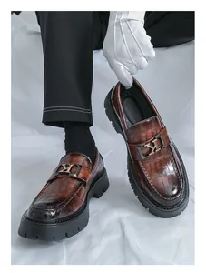 Close-up detail of brown crocodile-patterned thick sole men's loafers with metal buckle