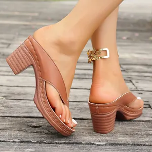Close-up view of elegant brown chunky high heel thong sandals worn on a rustic wooden deck