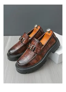 Macro view of brown crocodile-patterned leather loafers with thick soles and metal buckle