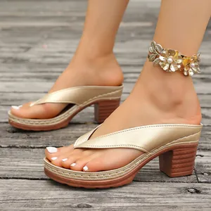 Elegant gold thong platform sandals with thick high heels worn on a rustic wooden deck