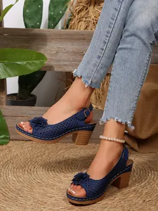 Detailansicht blaue Sandaletten mit Lochmuster, Blumen-Deko und Blockabsatz