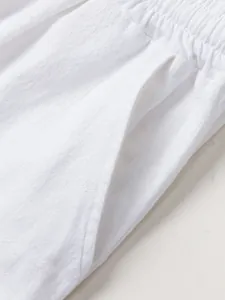 Close-up of white cotton linen trousers with elastic waistband and side pocket detail