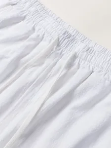 Close-up detail of white cotton linen trousers showing elastic waistband and drawstring