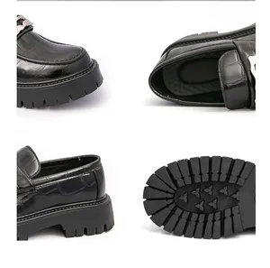 Vue détaillée de mocassins noirs à motif crocodile avec semelle crantée et boucle en métal.