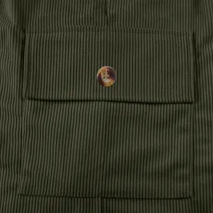 Primo piano di una tasca di camicia in velluto a coste verde oliva con bottone marrone