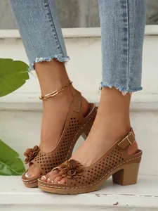 Detailansicht brauner Sandalen mit Blockabsatz, Laserschnitt-Muster und 3D-Blumendekor