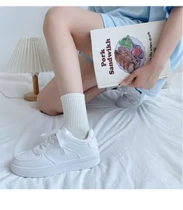 Lifestyle detail of classic white sneakers for women on soft bedding