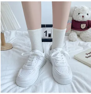 White casual board shoes worn with ribbed socks displayed in a cozy indoor scene