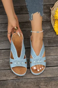 Detail of light blue women's wedge sandals with hollowed floral design and platform sole.