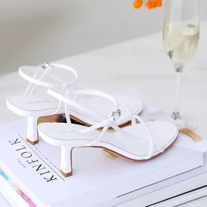 Elegant white kitten heel sandals with thin straps on a lifestyle background