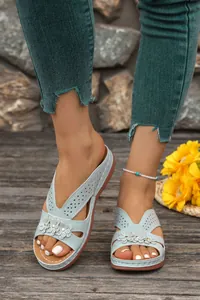 Detailed close-up of light blue wedge sandals with floral appliques and cutouts