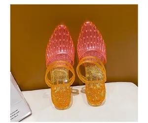 Macro view of pink and orange glitter jelly sandals with a pointed toe and double straps.
