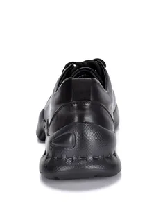 Detalle de vista trasera de zapatillas casuales de cuero negro para hombre con suela texturizada.
