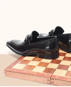 Λεπτομερής πλάγια όψη μαύρων δερμάτινων loafers με μεταλλική αγκράφα σε σκακιέρα