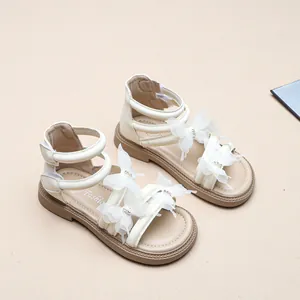 Detailansicht weißer Mädchensandalen mit Spitzen-Schmetterlingen und Strasssteinen.