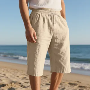 Close-up of men's beige linen drawstring shorts worn on a sunny beach background