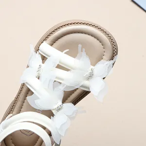 Detailansicht weißer Netz-Schmetterlingsbögen mit Strasssteinen auf Mädchen Sandalen.
