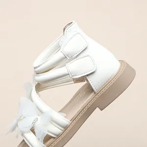 Nahaufnahme weißer Mädchen-Prinzessin-Sandalen mit Spitzen-Schmetterlingsschleife