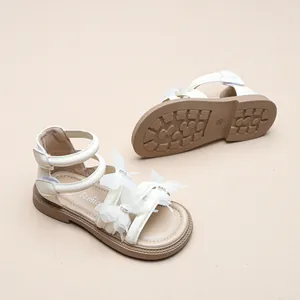 Nahaufnahme weißer Mädchensandalen mit zarten Schmetterlings-Applikationen und rutschfester Sohle.