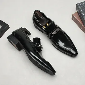 Elegantes mocasines de cuero negro pulido para hombre con hebilla de metal y punta fina.