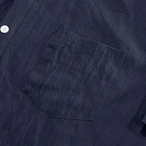 Close-up of chest pocket and linen texture on navy short sleeve shirt.