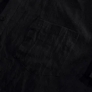 Detailed close-up showing the black linen fabric texture and pocket on this men's casual shirt