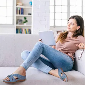 Stylish woman wearing blue floral wedge sandals in a bright, modern living room.