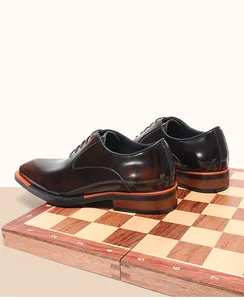 Chaussures richelieu élégantes en cuir marron avec bout carré sur un échiquier en bois