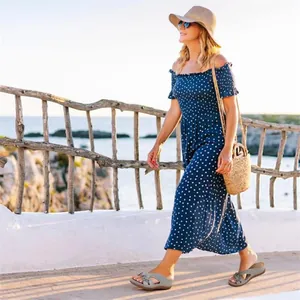 Mujer caminando con sandalias de cuña grises con flores en un sendero costero soleado