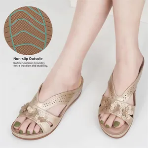 Detail view of non-slip rubber outsole and flower decorations on golden wedge sandals.