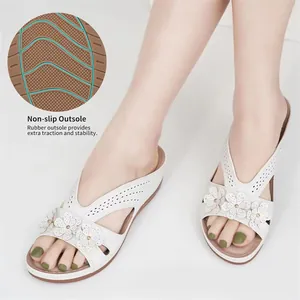 Detailansicht der rutschfesten Gummisohle dieser weißen floralen Keilsandalen für den Strand