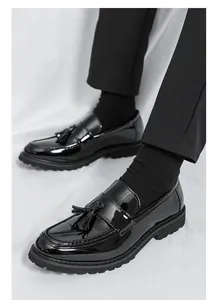 Primer plano de mocasines de charol negro con borlas para hombre, diseño clásico inglés.