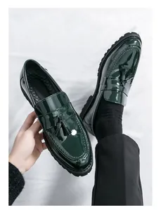 Detalle de mocasines con borlas en charol verde oscuro y suela de estilo militar.
