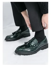 Primer plano de mocasines con borlas de charol verde oscuro para hombre con suelas negras