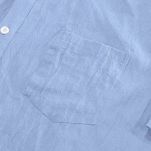 Detailed close-up of light blue linen shirt pocket showing high-quality fabric texture.