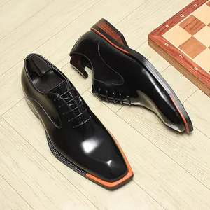 Détail de chaussures Oxford pour hommes en cuir verni noir avec bout carré et trépointe orange.