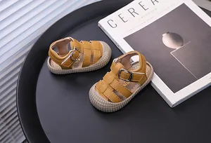 Close-up of yellow baby soft sole sandals with hollow-out design and buckle strap.