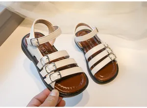 Stylish white Roman sandals for girls with buckle straps and non-slip brown soles.