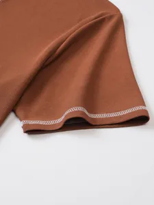 Close-up of white decorative stitching on brown waffle texture men's Henley shirt sleeve