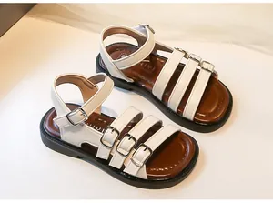 Close-up of white girl's Roman sandals with multiple buckle straps and brown insole