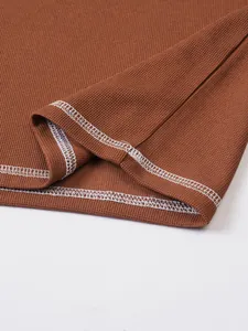 Close-up of brown textured Henley shirt featuring white contrast stitching detail.